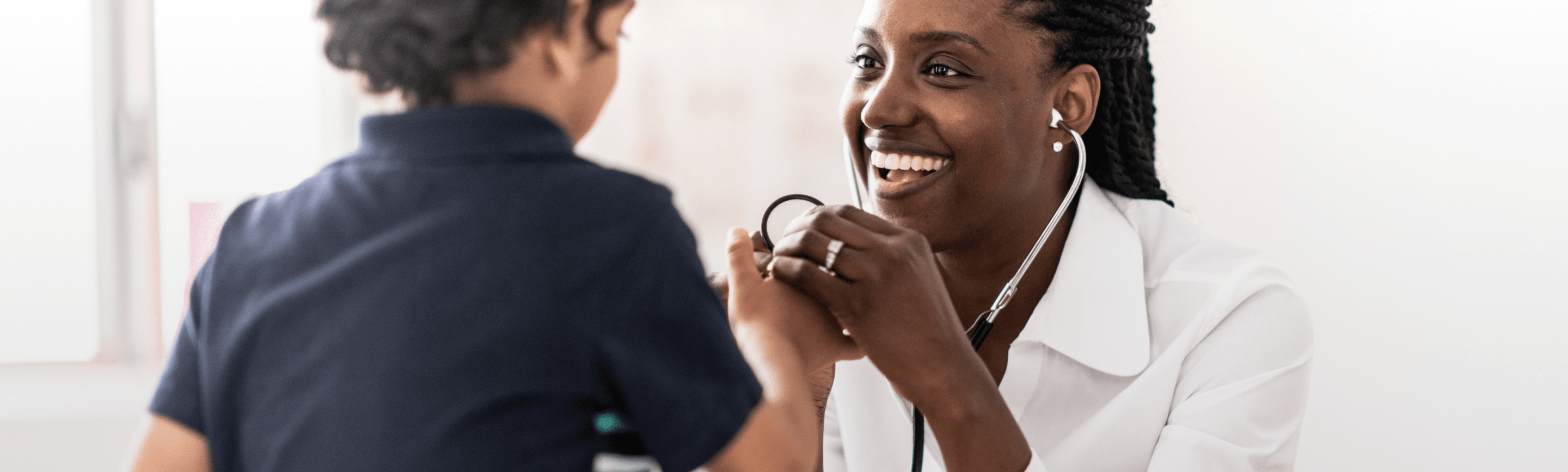 Médica que le sonríe a un niño mientras le toma la presión arterial.