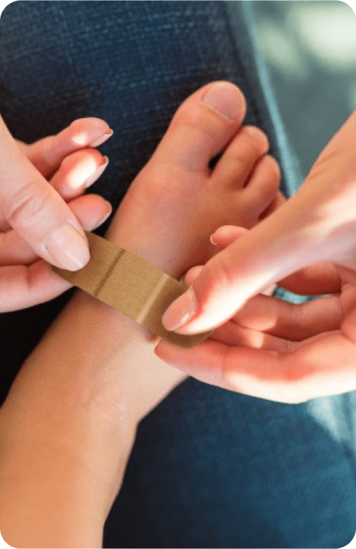 Adulto que coloca un Marca BAND-AID® Apósito en el pie a un niño.