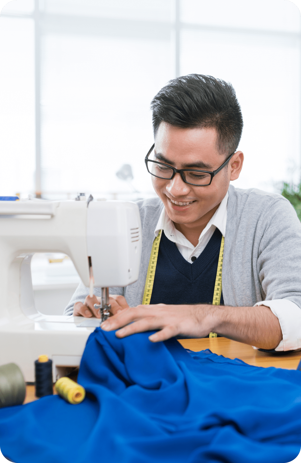 Hombre que sonríe mientras usa una máquina de coser.